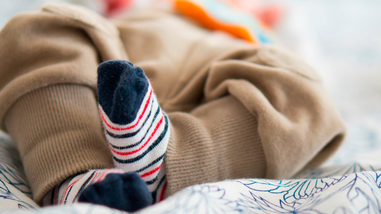 Un bébé porte des chaussettes aux pieds.