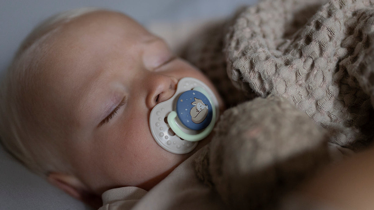 Bébé dormant avec une sucette, illustrant l’apprentissage du sommeil nocturne