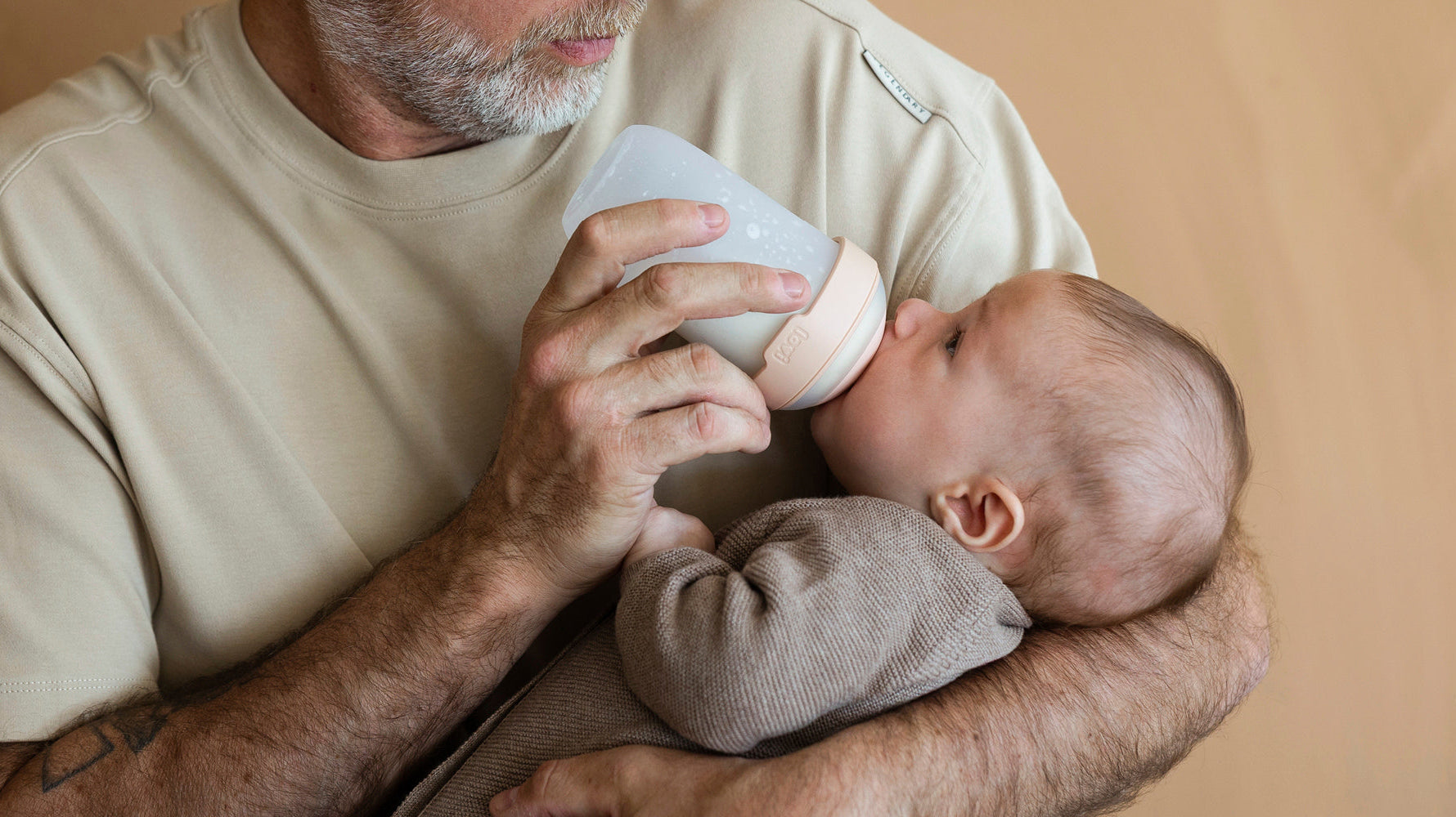 Père donnant le biberon Mammafeel à son bébé, biberon testé par les familles et noté 8,4 sur 10 pour sa douceur et facilité d’utilisation.