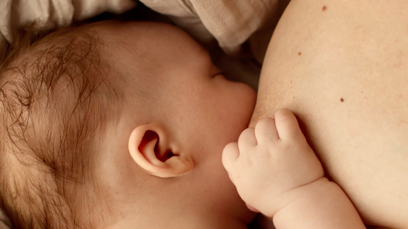 Nouveau-né tétant au sein de sa mère, illustrant l’allaitement et le lien affectif entre la mère et le bébé.