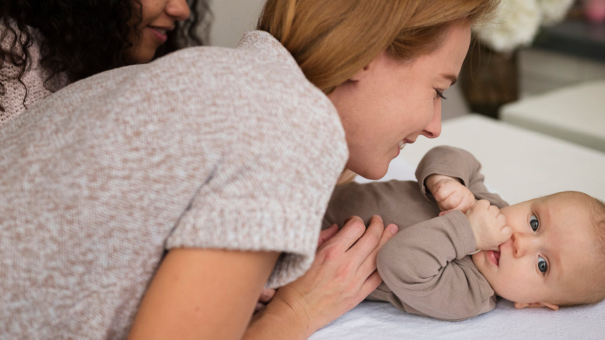 Maman jouant avec son bébé sur le lit, illustrant le développement et les premières étapes de l’enfant.