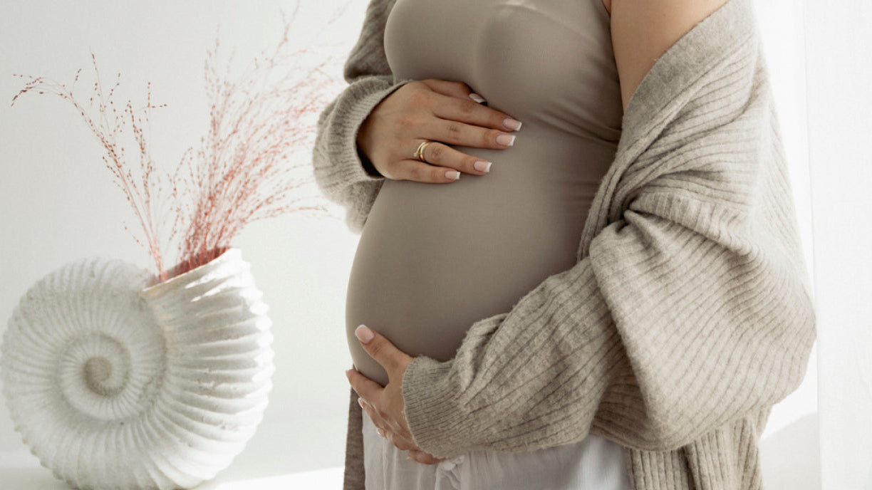 Femme enceinte posant les mains sur son ventre, préparant sa grossesse et sa future accouchement naturel avec sérénité.