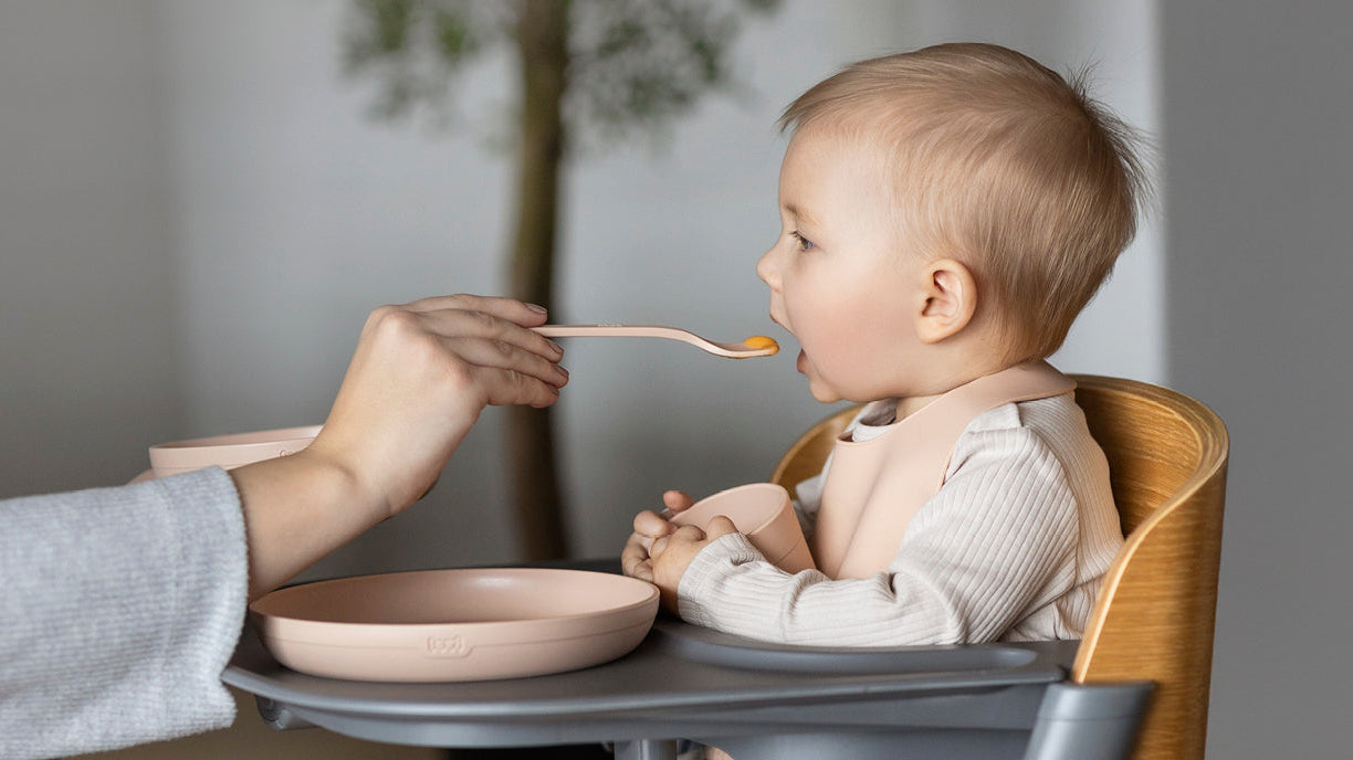 Bébé mange des pommes de terre préparées pour bébé dans sa chaise haute