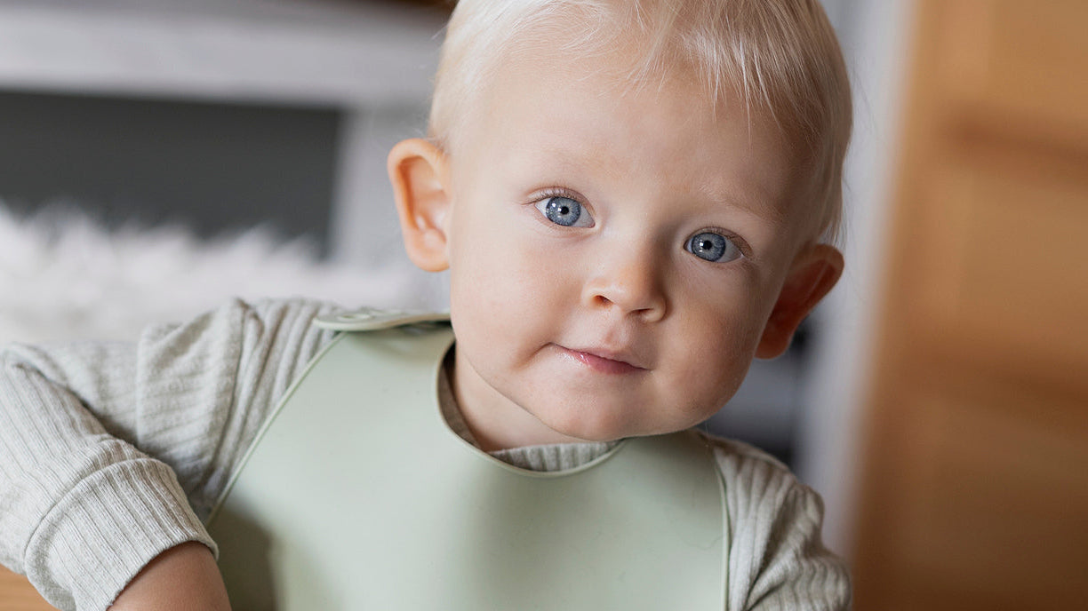 Petit garçon portant un bavoir Difrax Lovi, prêt à déguster un repas sain à base de légumineuses, symbole d’une alimentation équilibrée et adaptée aux tout-petits.