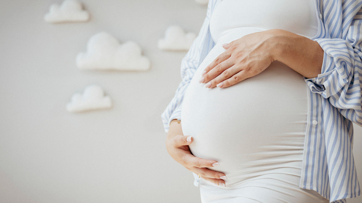 Femme enceinte tenant son ventre, symbolisant la grossesse et le bien-être maternel.