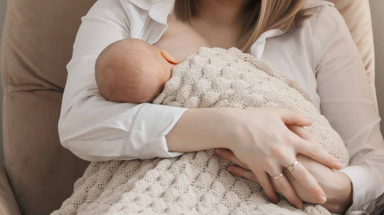 Bébé reçoit le lait maternel au sein de sa mère, illustrant l’importance de la surveillance de la prise de poids et du soutien à l’allaitement pour un développement sain.