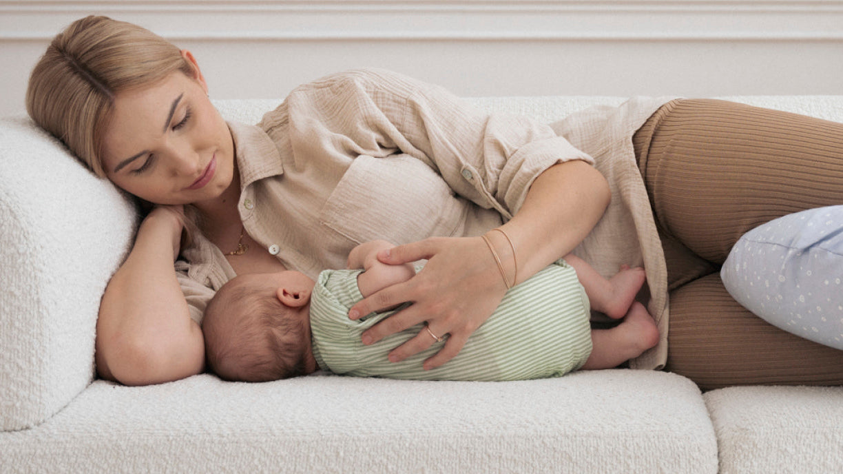 Maman tient son bébé dans ses bras en se reposant après l’accouchement, illustrant les défis et les soins nécessaires pendant la période post-partum.