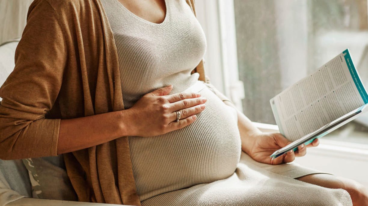 Femme enceinte posant la main sur son ventre, illustrant les expériences et changements possibles lors d’une deuxième grossesse.