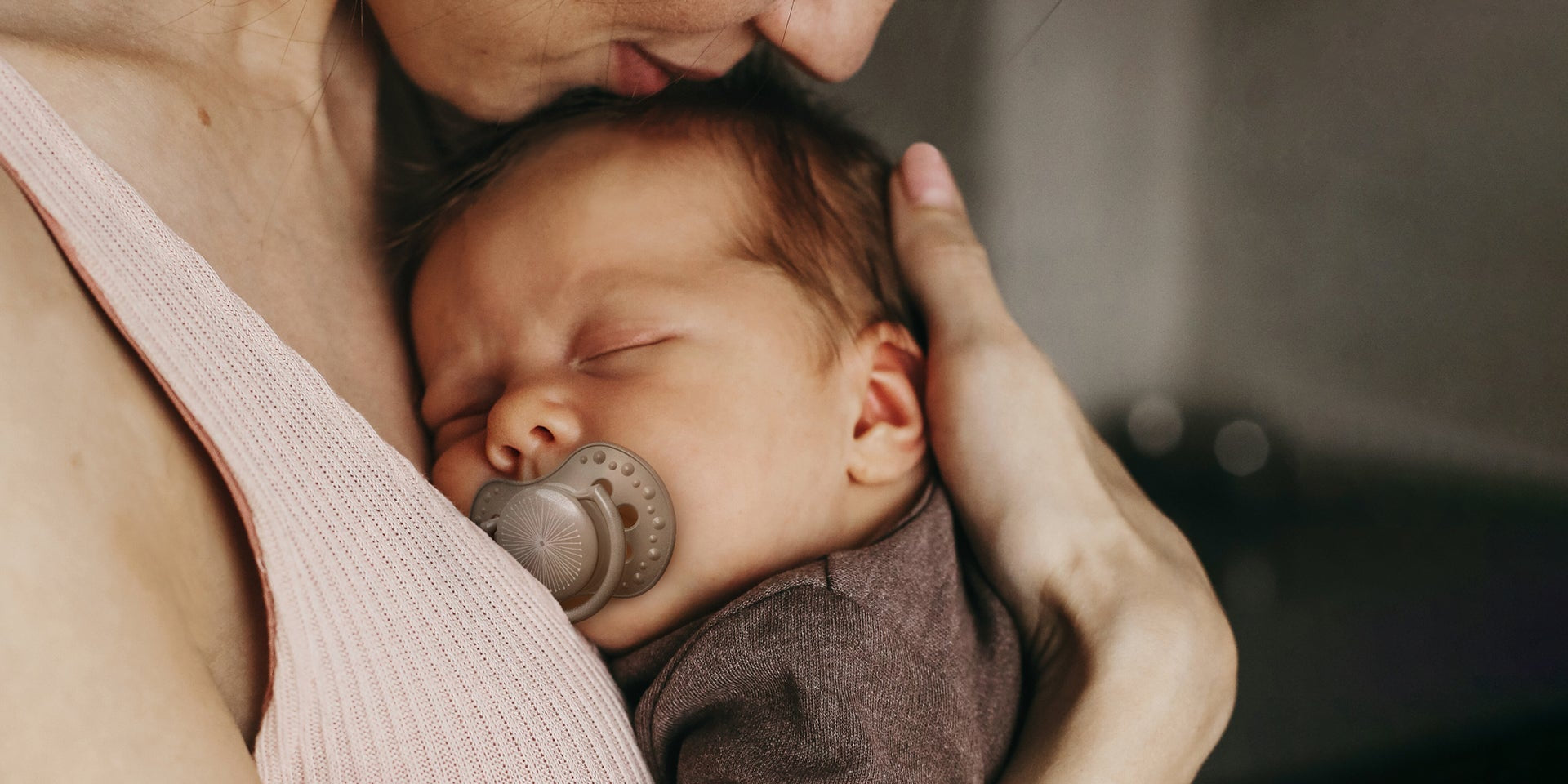 Un nouveau-né est allongé contre la poitrine de sa maman. Le bébé a une sucette Difrax LOVI pour nouveau-né.