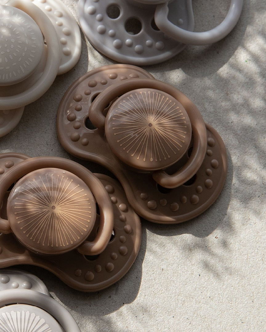 Une collection de sucettes dans des tons naturels allant de l’ivoire au brun clair. Les sucettes font partie de la collection Difrax LOVI dynamic pacifiers.