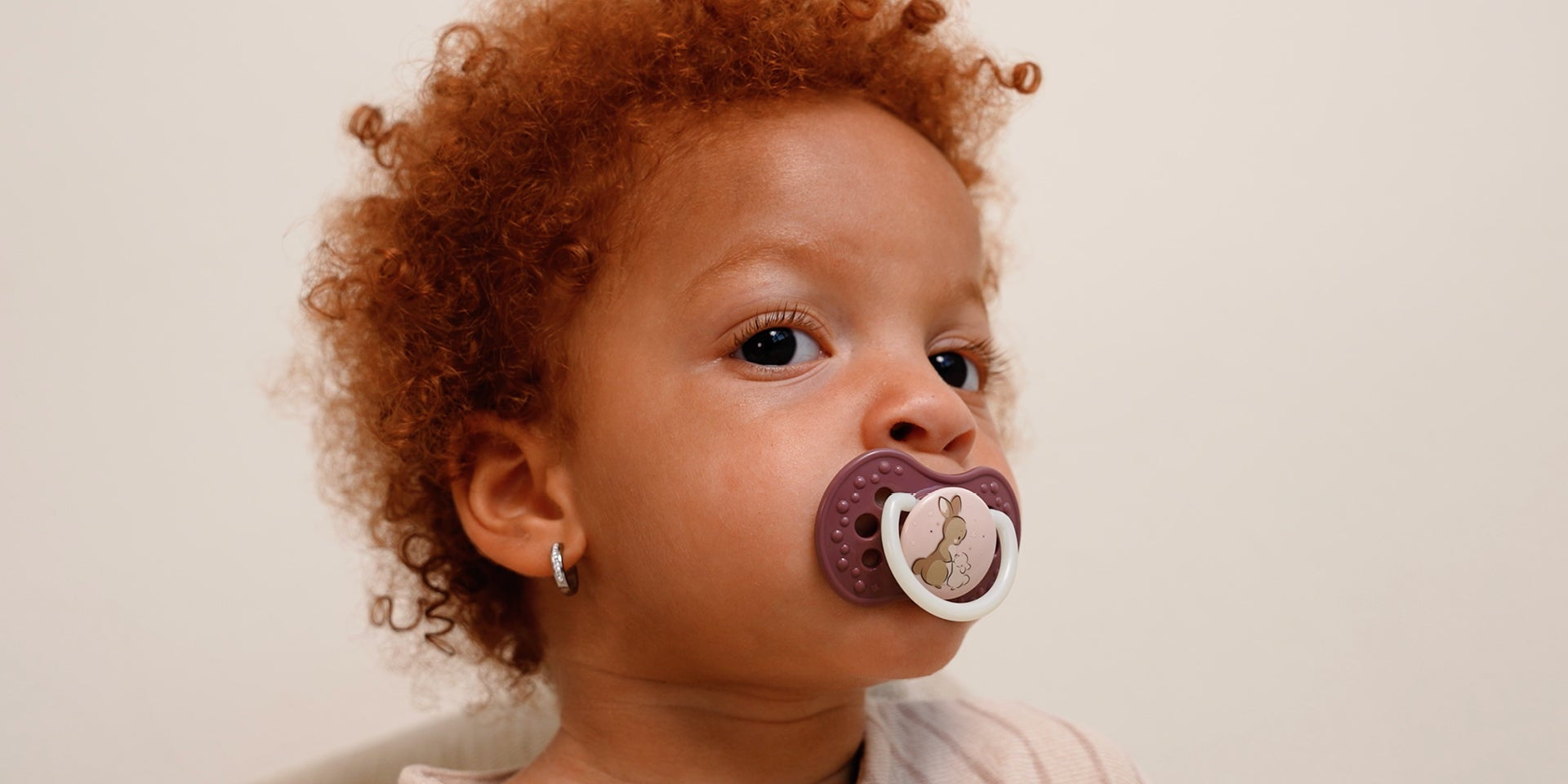 Gros plan sur une petite fille de 18 mois avec une sucette. La sucette fait partie de la collection Difrax Lovi Night&Day