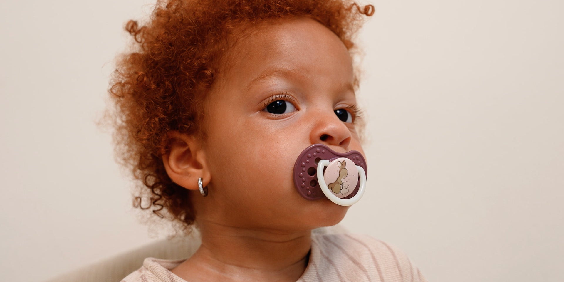 Gros plan sur une petite fille de 18 mois avec une sucette. La sucette fait partie de la collection Difrax Lovi Night&Day