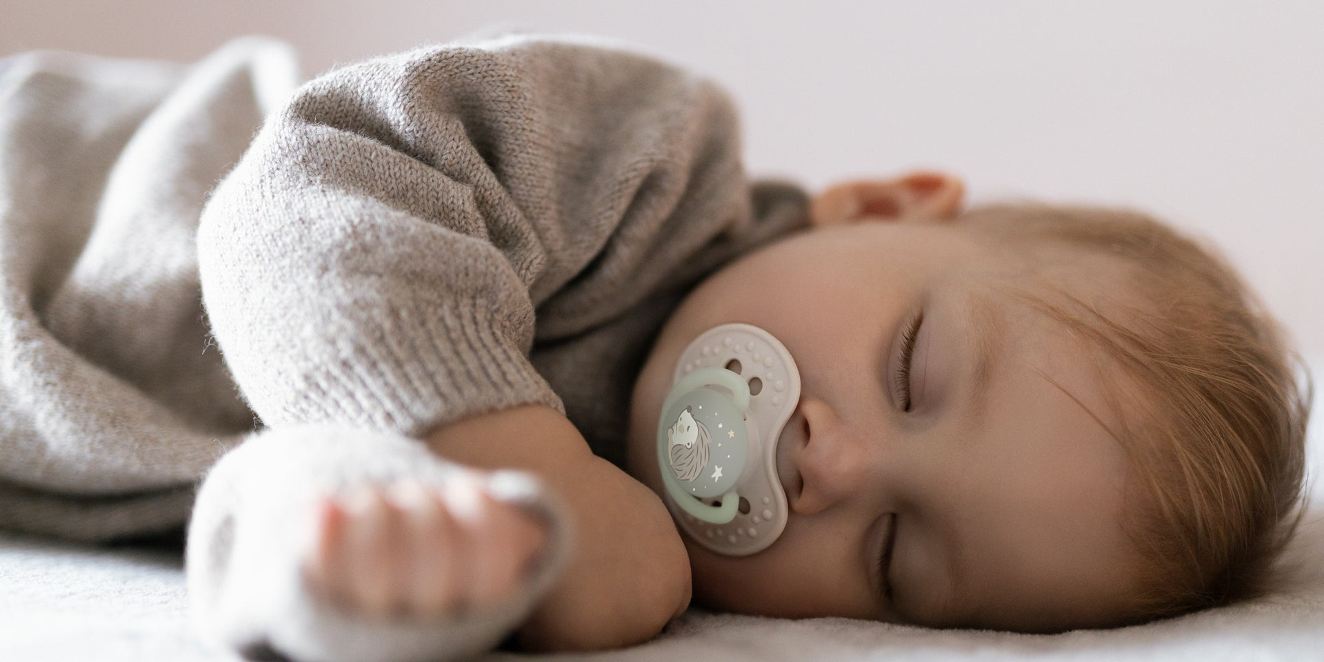 Un tout-petit dort dans son lit avec une sucette Difrax LOVI de la collection Night&Day.
