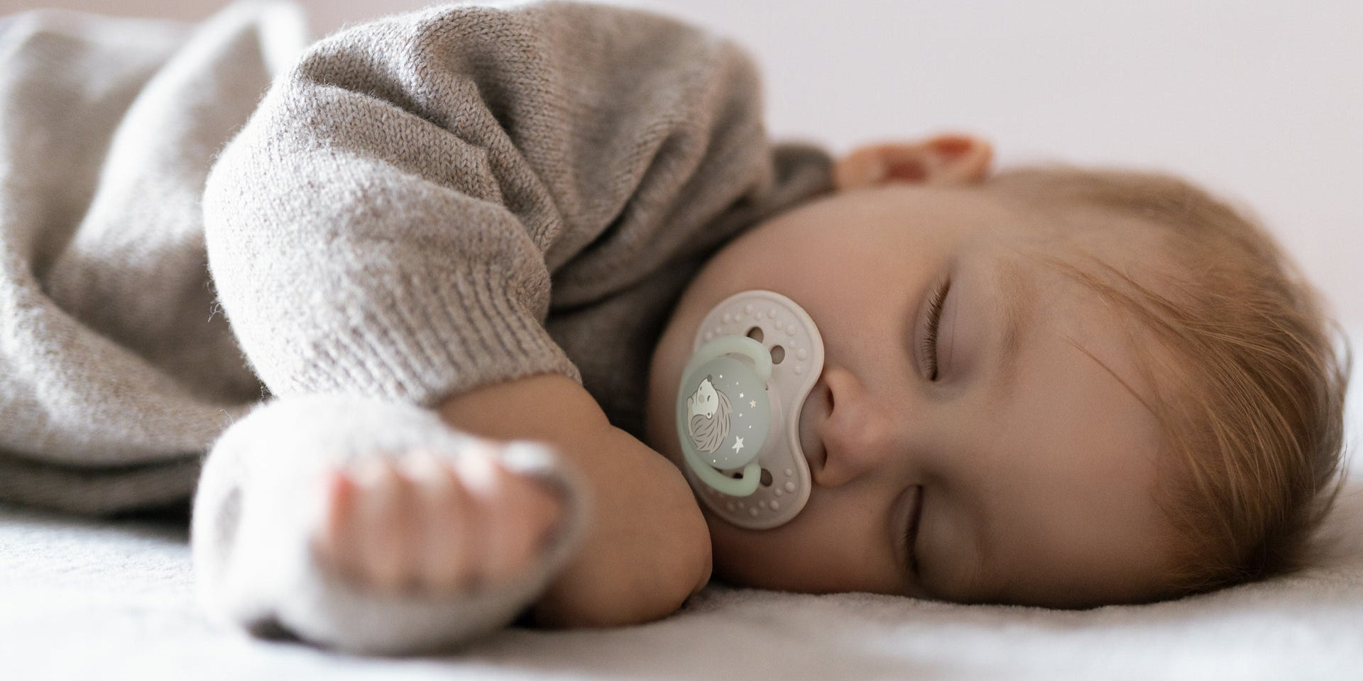 Un tout-petit dort dans son lit avec une sucette Difrax LOVI de la collection Night&Day.