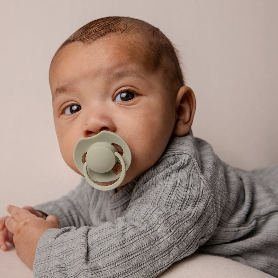 Un tout-petit avec une sucette ivoire Difrax LOVI de la collection Prime.