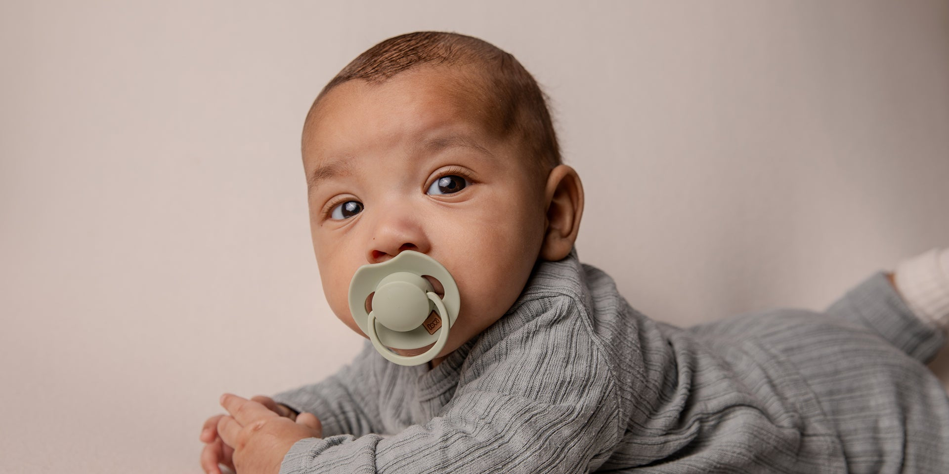 Un tout-petit avec une sucette ivoire Difrax LOVI de la collection Prime.