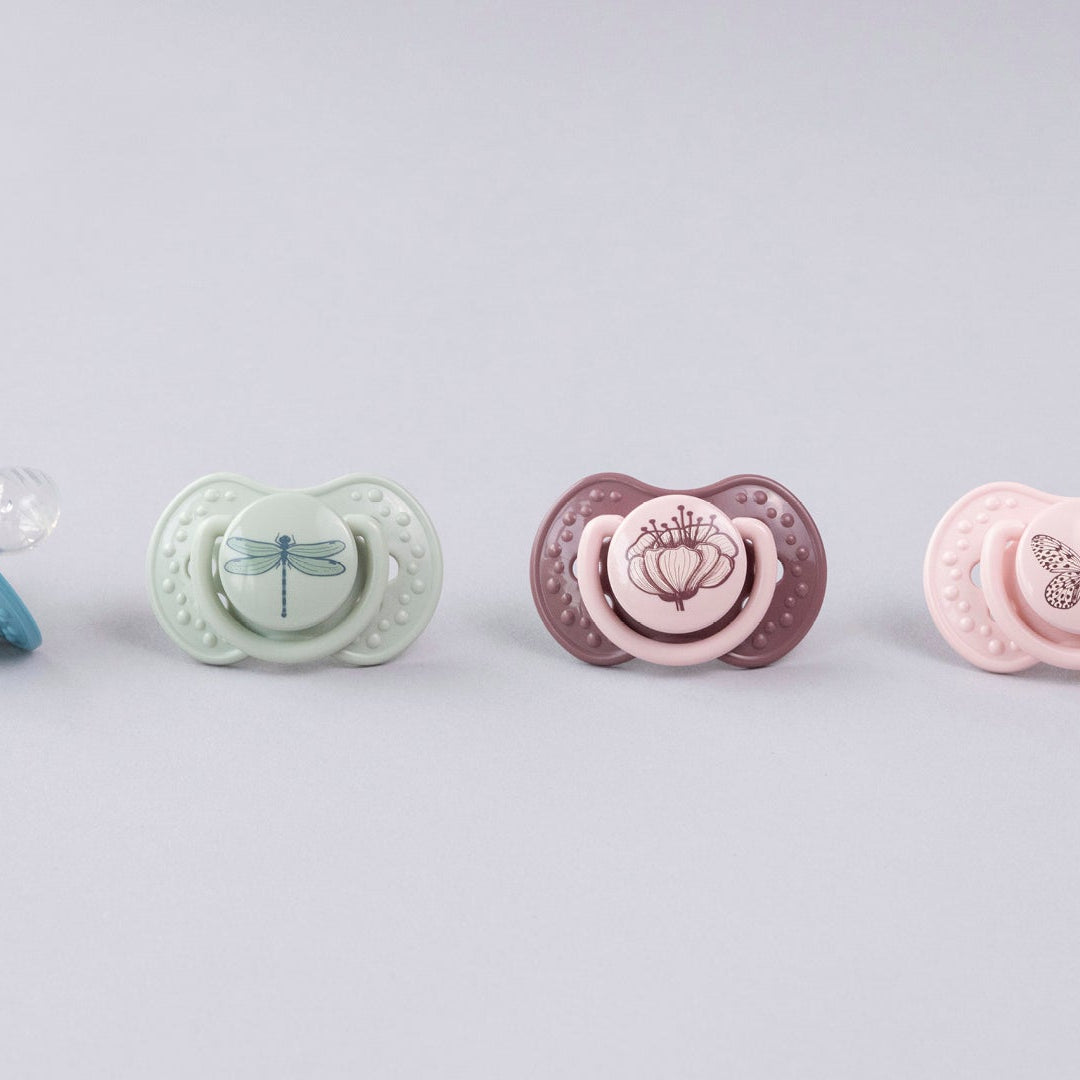 Une sucette bleue et verte sur une serviette. Les sucettes font partie de la collection Difrax LOVI Botanic.