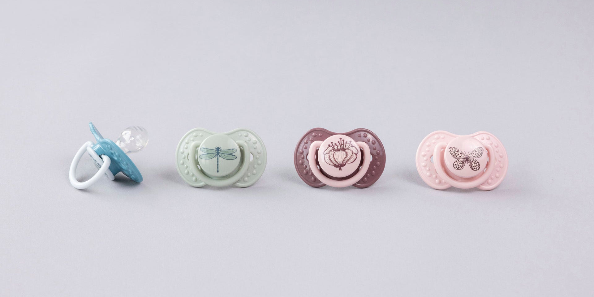 Une sucette bleue et verte sur une serviette. Les sucettes font partie de la collection Difrax LOVI Botanic.