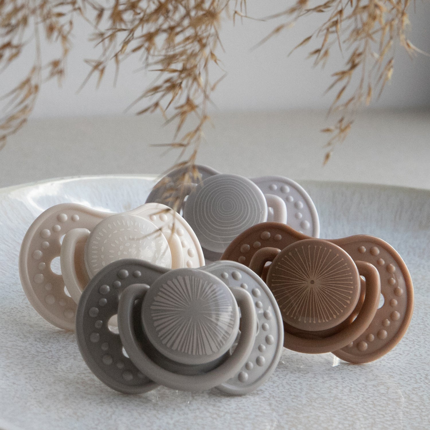 Quatre tétines de la collection Harmony en couleurs gris, crème et marron, adaptées pour bébé