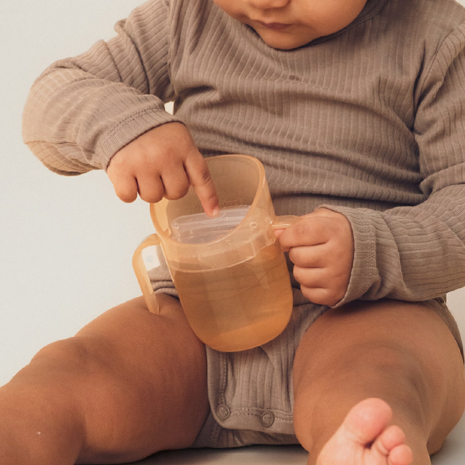 Enfant curieux avec le gobelet Genius couleur nude, gros plan