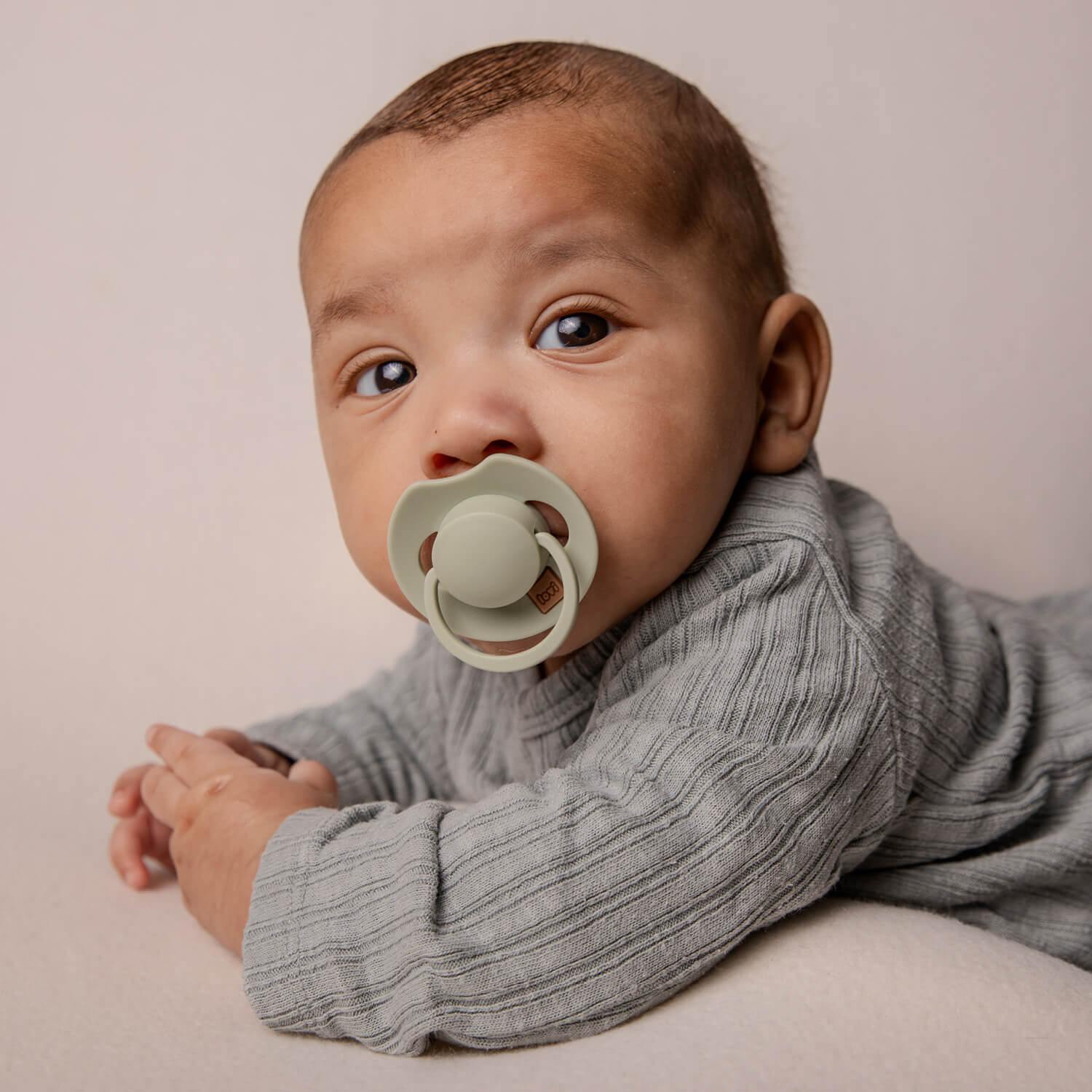 Un bébé couché avec le Dynamic Sucette Prime pistache