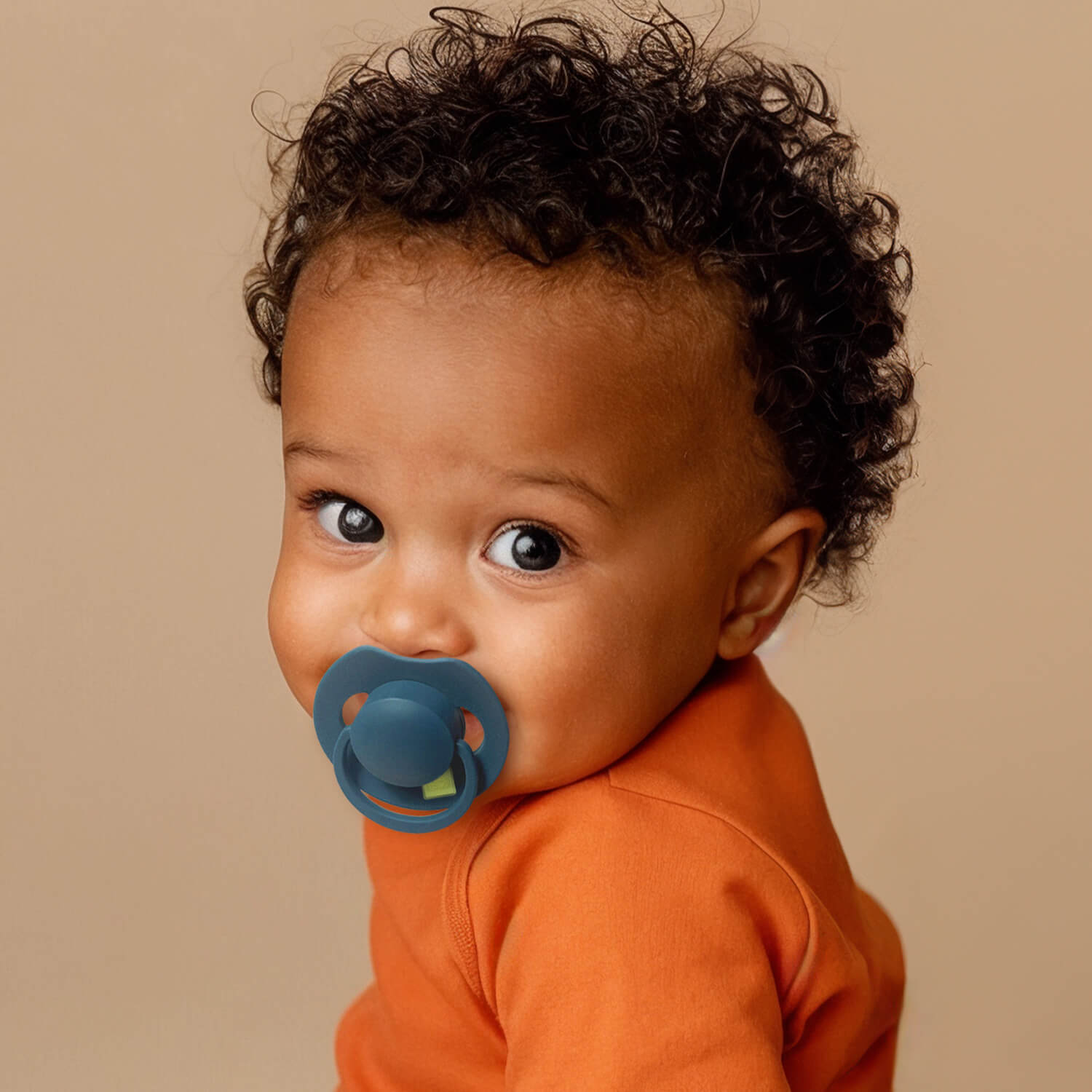 Un petit garçon heureux assis avec la Sucette dynamique Prime bleue