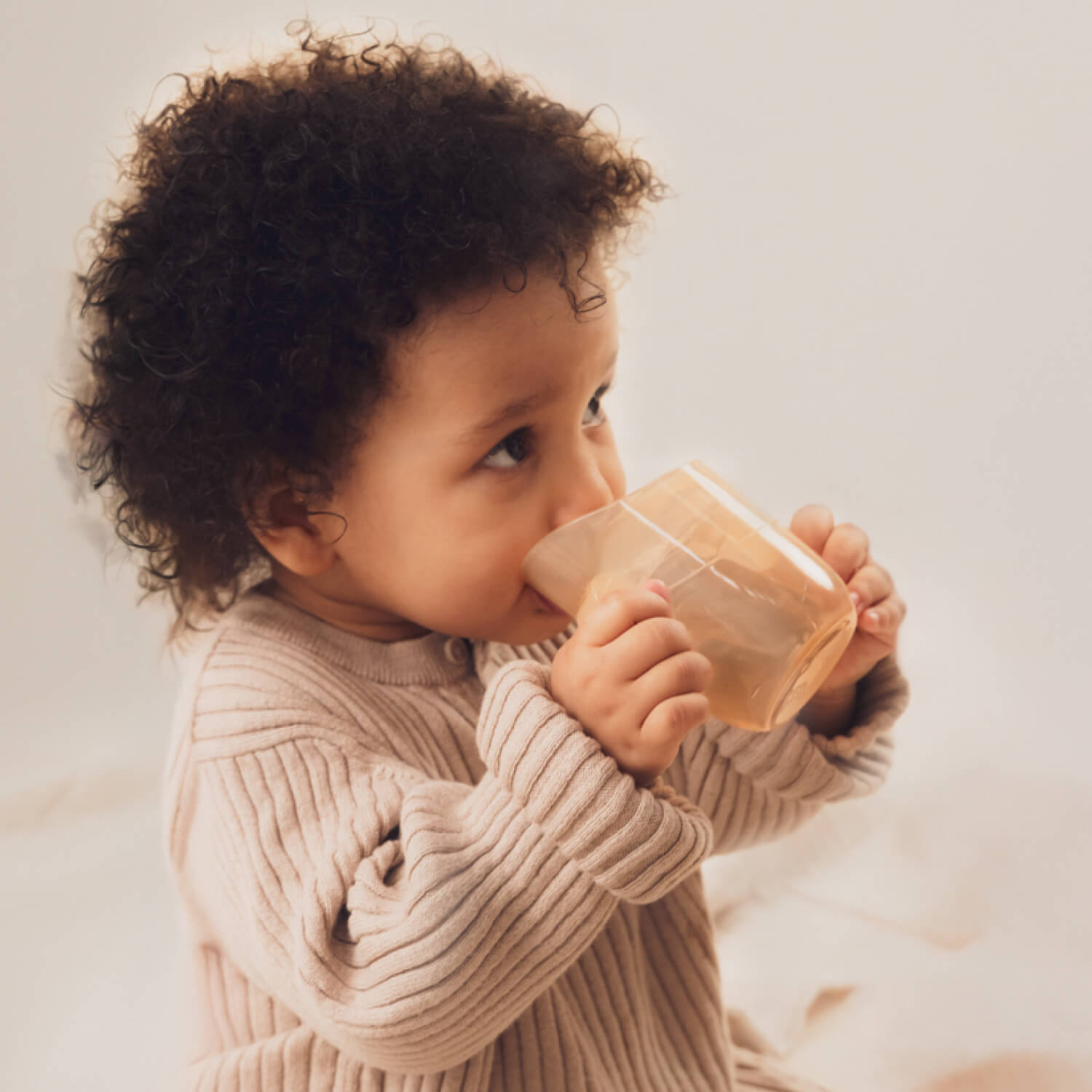 Jeune fille boit de manière autonome avec le gobelet d’apprentissage Difrax LOVI Genius, adapté dès 6 mois – favorise le développement moteur
