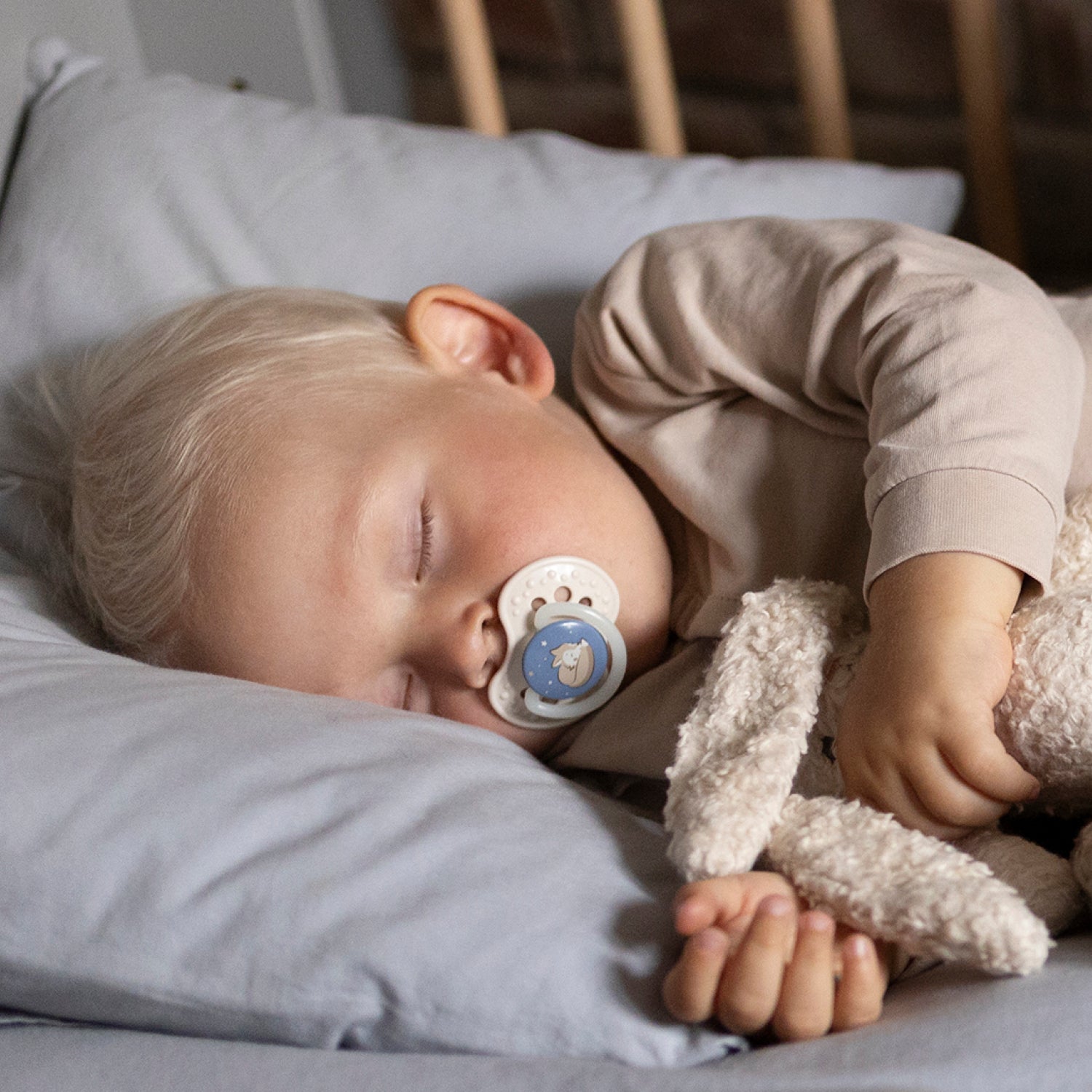 Un petit garçon qui dort avec sa sucette de jour et de nuit bleue.