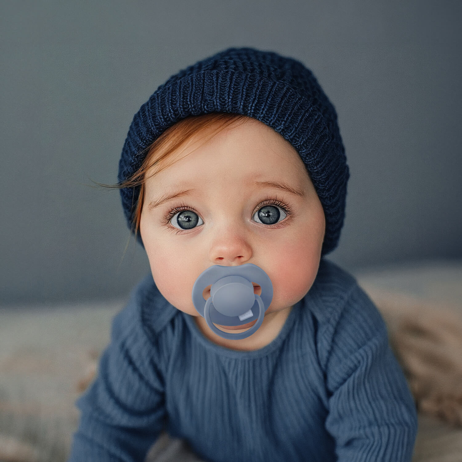 Un petit garçon heureux assis avec la Sucette dynamique Prime bleu bébé