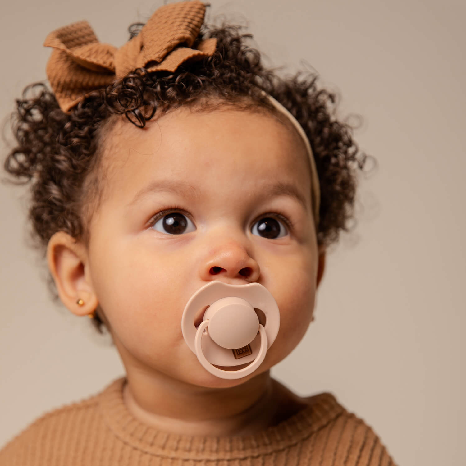Une petite fille heureuse assise avec la Sucette dynamique Prime Nude