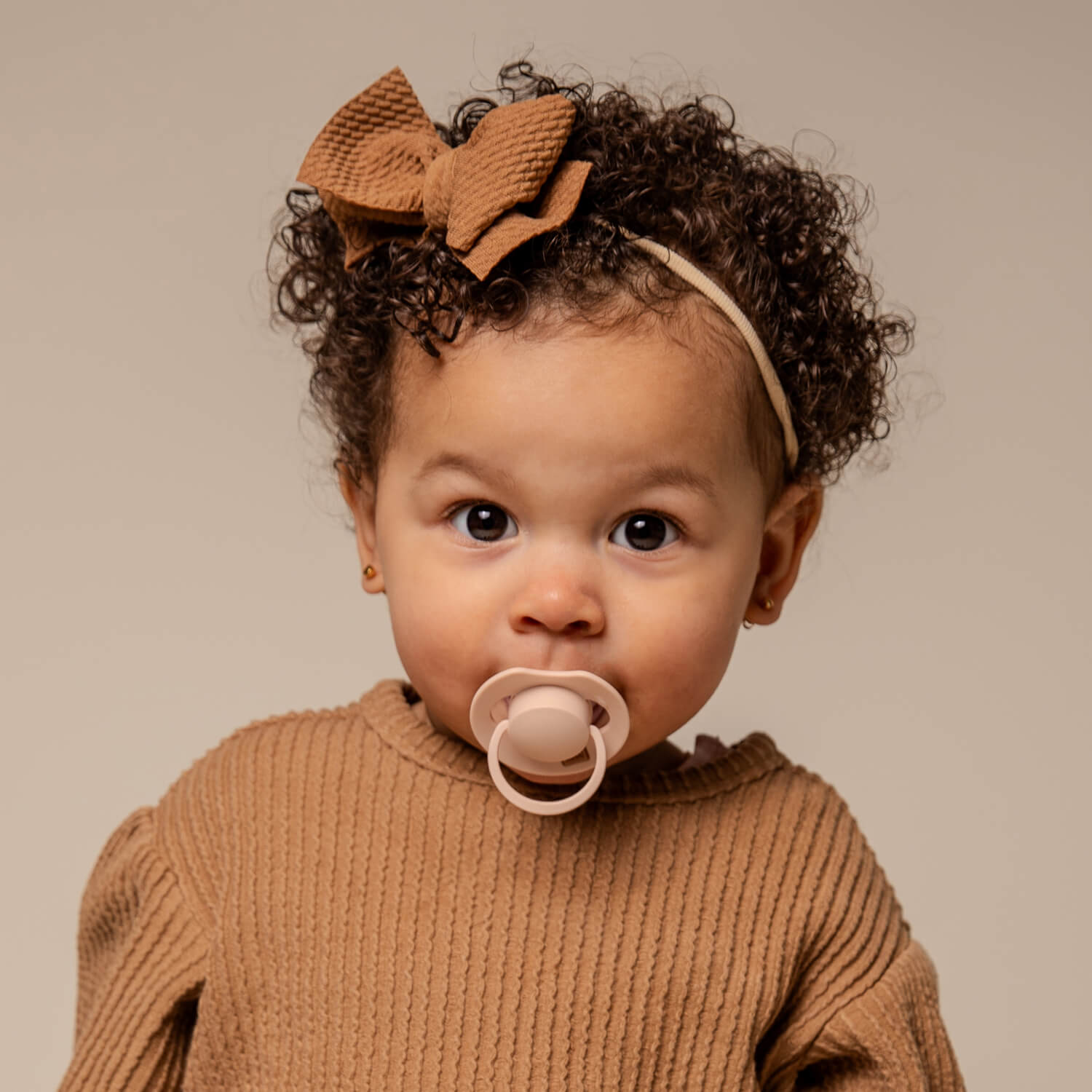 Une petite fille heureuse assise avec la Sucette dynamique Prime Nude