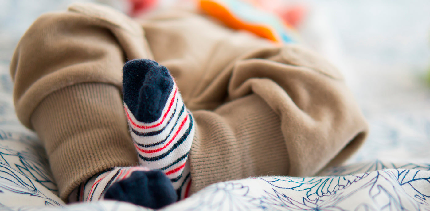 Un bébé porte des chaussettes aux pieds.