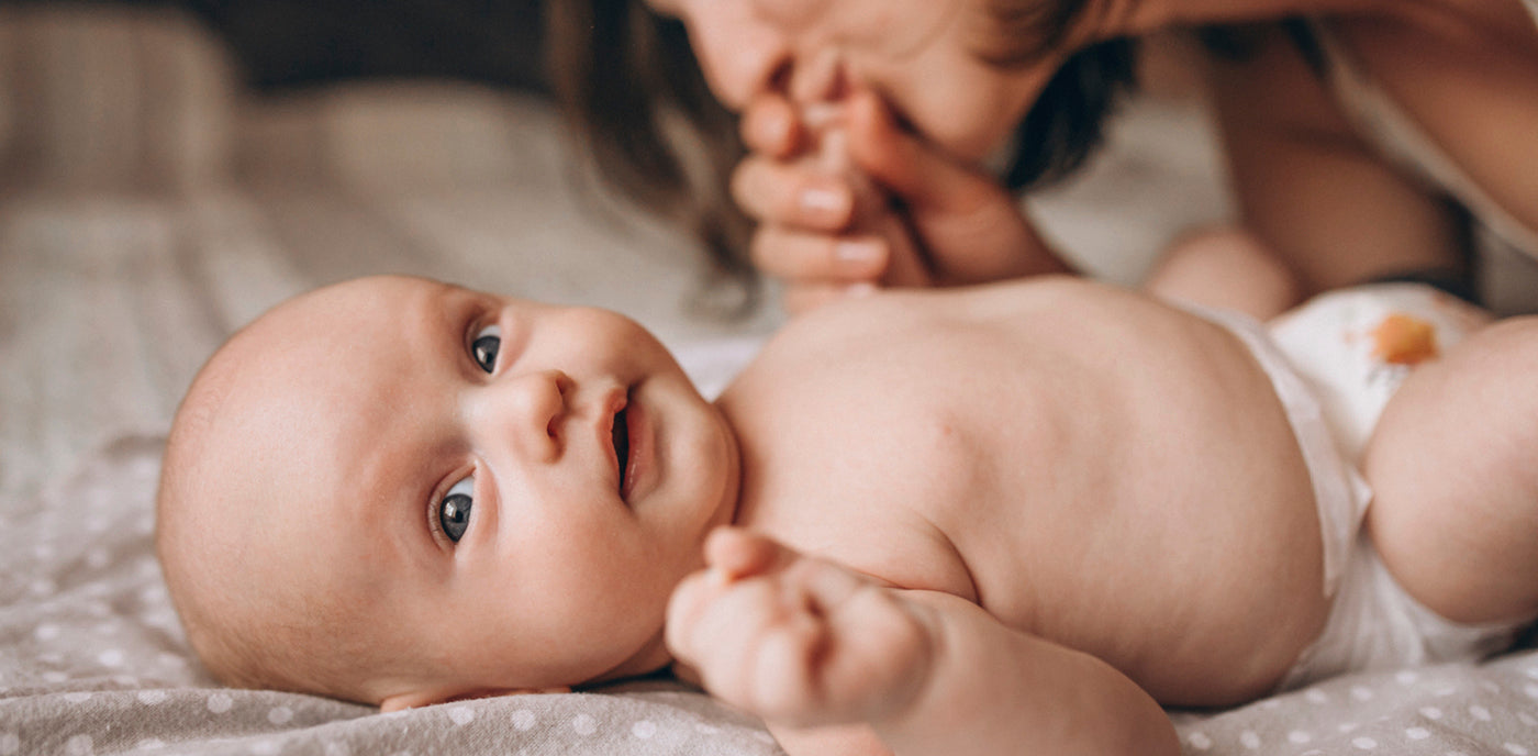 La mère donne un petit bisou à la main de son bébé