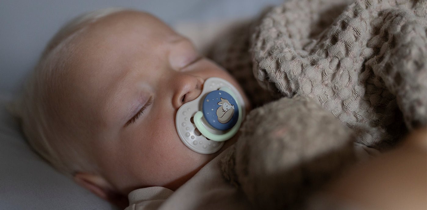 Bébé dormant avec une sucette, illustrant l’apprentissage du sommeil nocturne