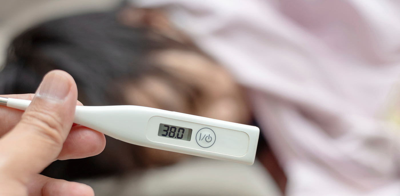 Une mère prend la température de son bébé avec un thermomètre. L’appareil indique 38 degrés, tandis que la mère observe attentivement son enfant.