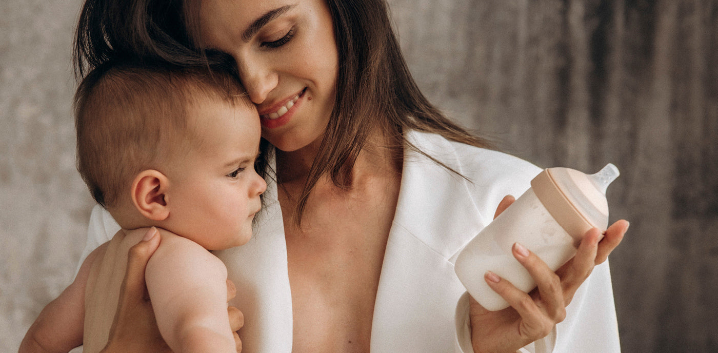 Maman tenant son bébé avec un biberon prêt pour une sortie