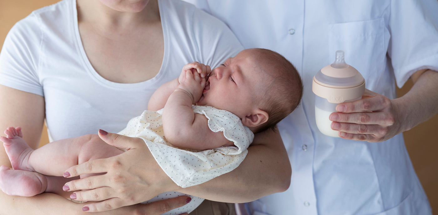 La mère soulève le bébé et le père tient un biberon Mammafeel de Difrax LOVI