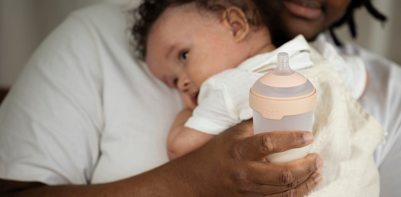 La sage-femme tient le bébé dans une main et un biberon Mammafeel de Difrax LOVI dans l’autre
