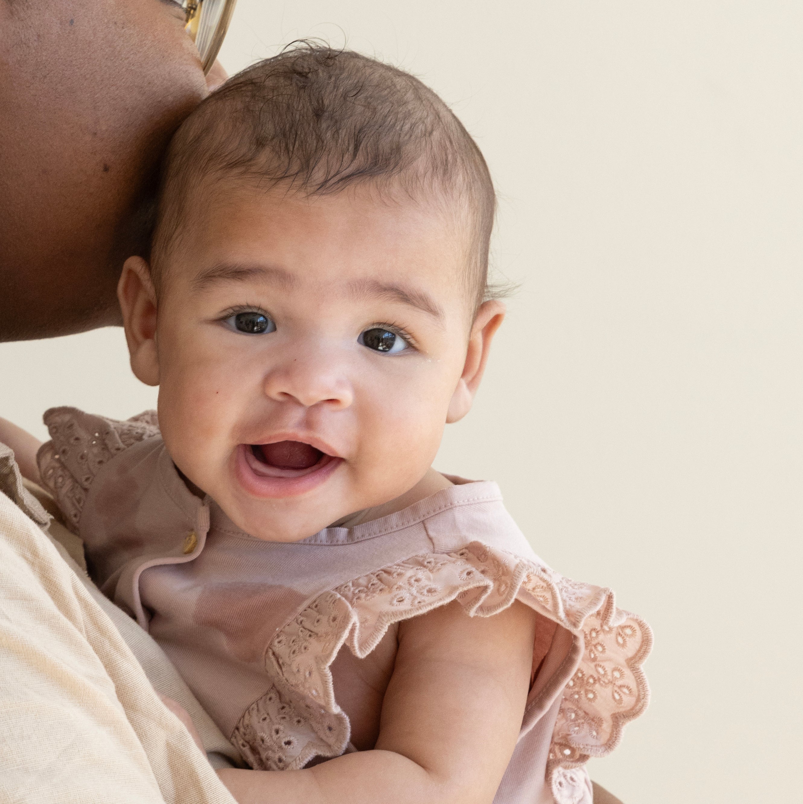 "Un bébé souriant est assis dans les bras de sa mèr