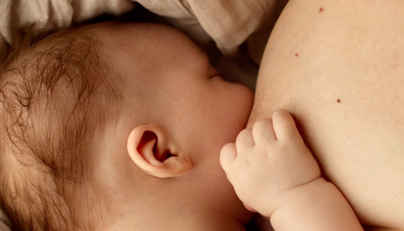 Nouveau-né tétant au sein de sa mère, illustrant l’allaitement et le lien affectif entre la mère et le bébé.