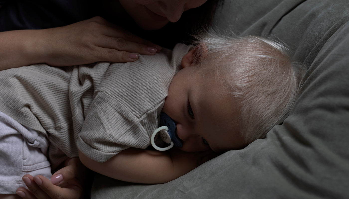 Bébé couché dans son lit, tenant un tétine, prêt pour le sommeil.