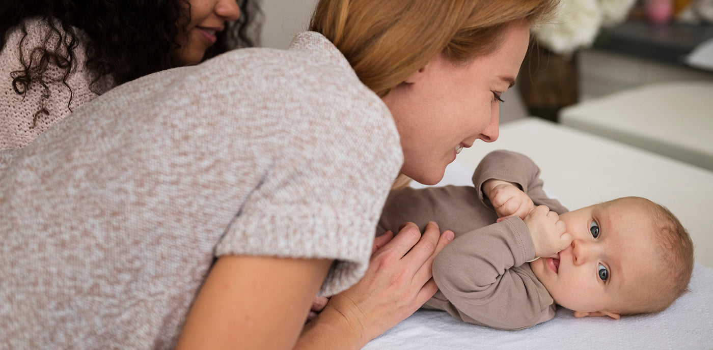 Maman jouant avec son bébé sur le lit, illustrant le développement et les premières étapes de l’enfant.