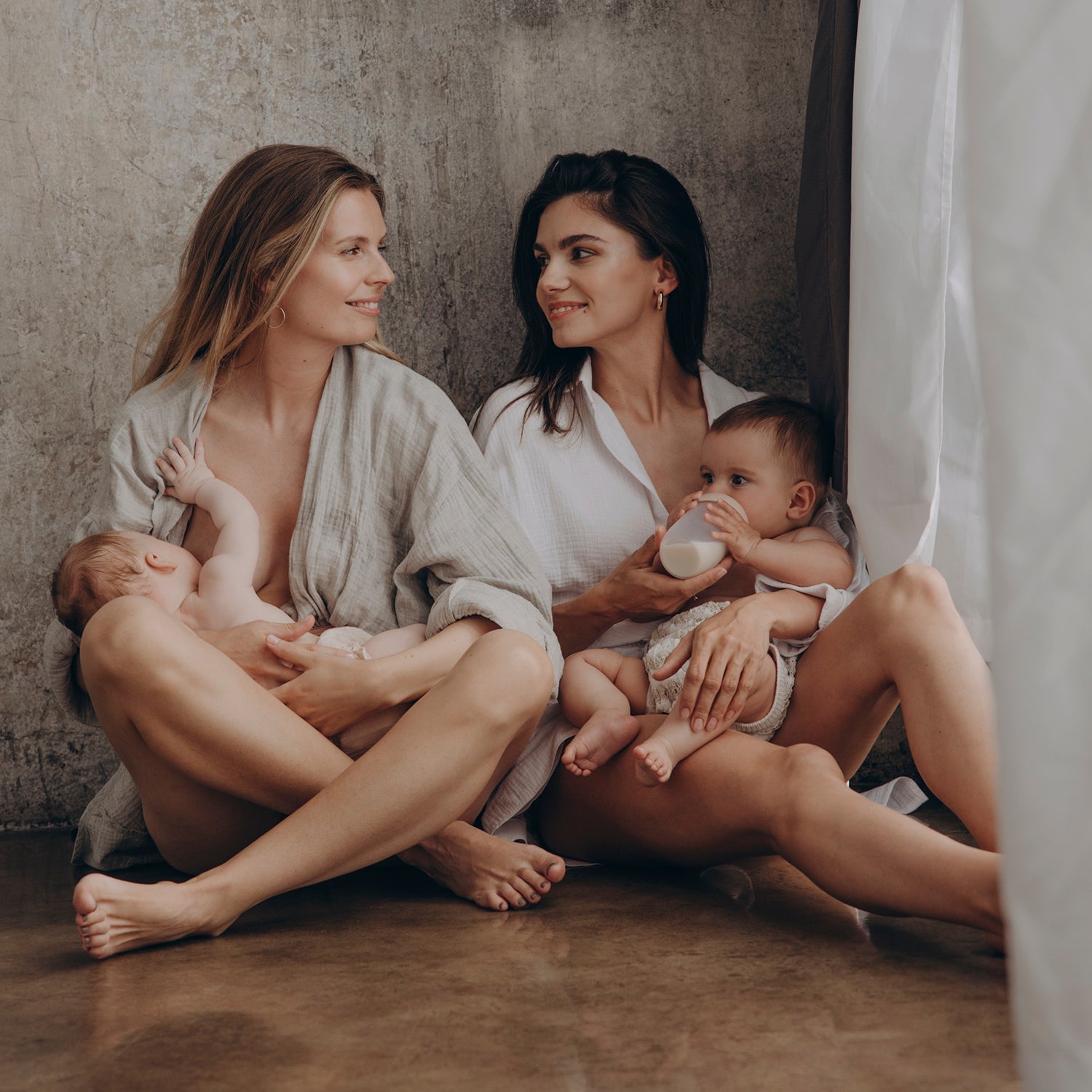 un nouveau-né est allaité par sa mère, et le second bébé, un garçon, est couché dans les bras de sa mère avec le biberon Difrax Lovi Mammafeel.