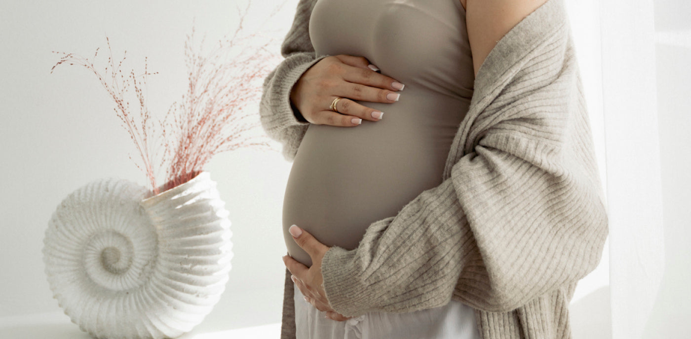 Femme enceinte posant les mains sur son ventre, préparant sa grossesse et sa future accouchement naturel avec sérénité.
