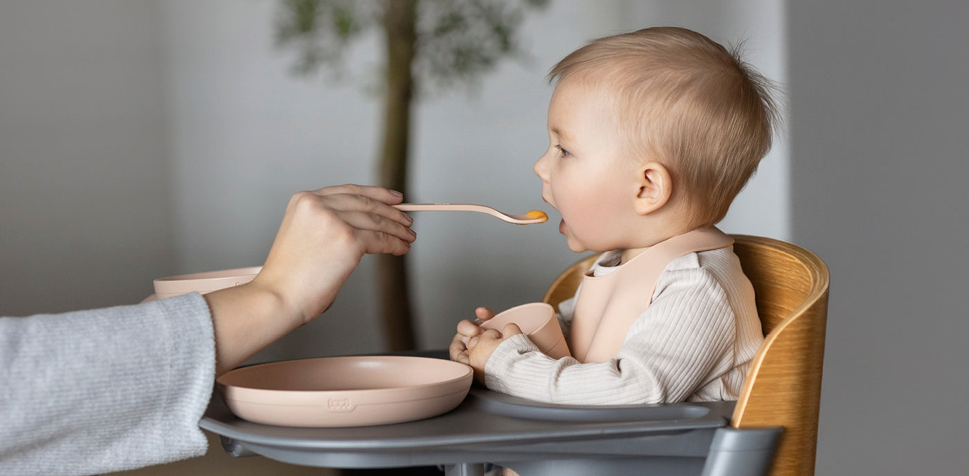 Bébé mange des pommes de terre préparées pour bébé dans sa chaise haute