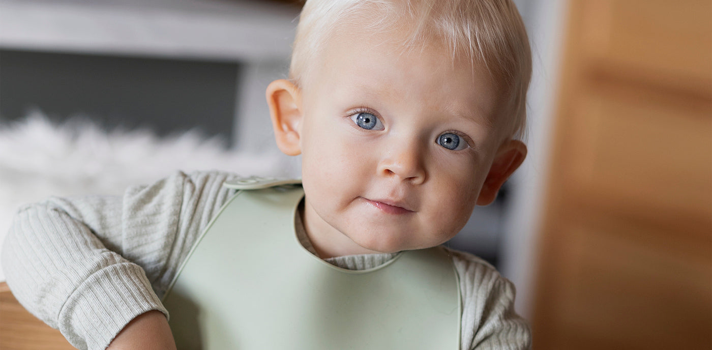 Petit garçon portant un bavoir Difrax Lovi, prêt à déguster un repas sain à base de légumineuses, symbole d’une alimentation équilibrée et adaptée aux tout-petits.