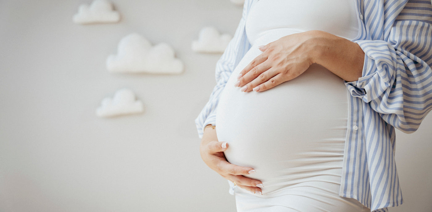 Femme enceinte tenant son ventre, symbolisant la grossesse et le bien-être maternel.