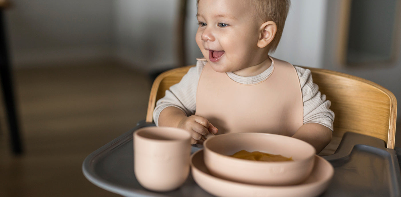 Bébé assis dans sa chaise haute, utilisant le set de repas Difrax Lovi, dégustant un repas préparé avec du lait infantile