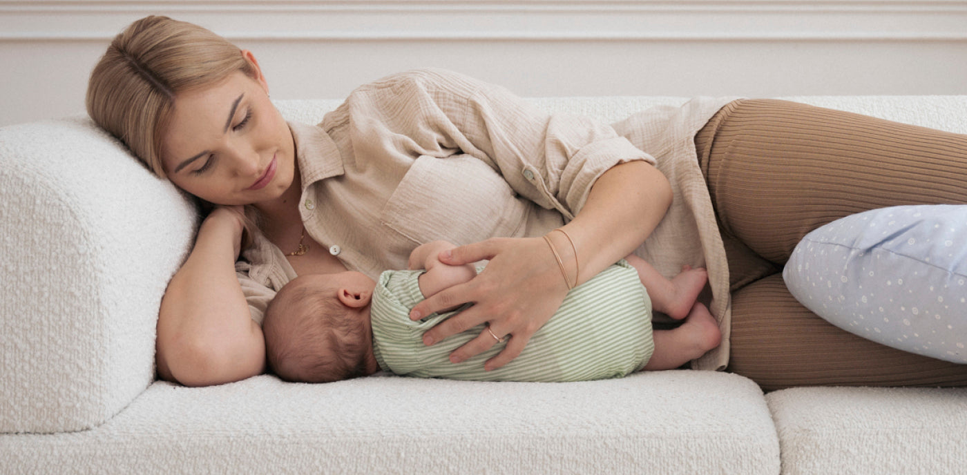 Maman tient son bébé dans ses bras en se reposant après l’accouchement, illustrant les défis et les soins nécessaires pendant la période post-partum.