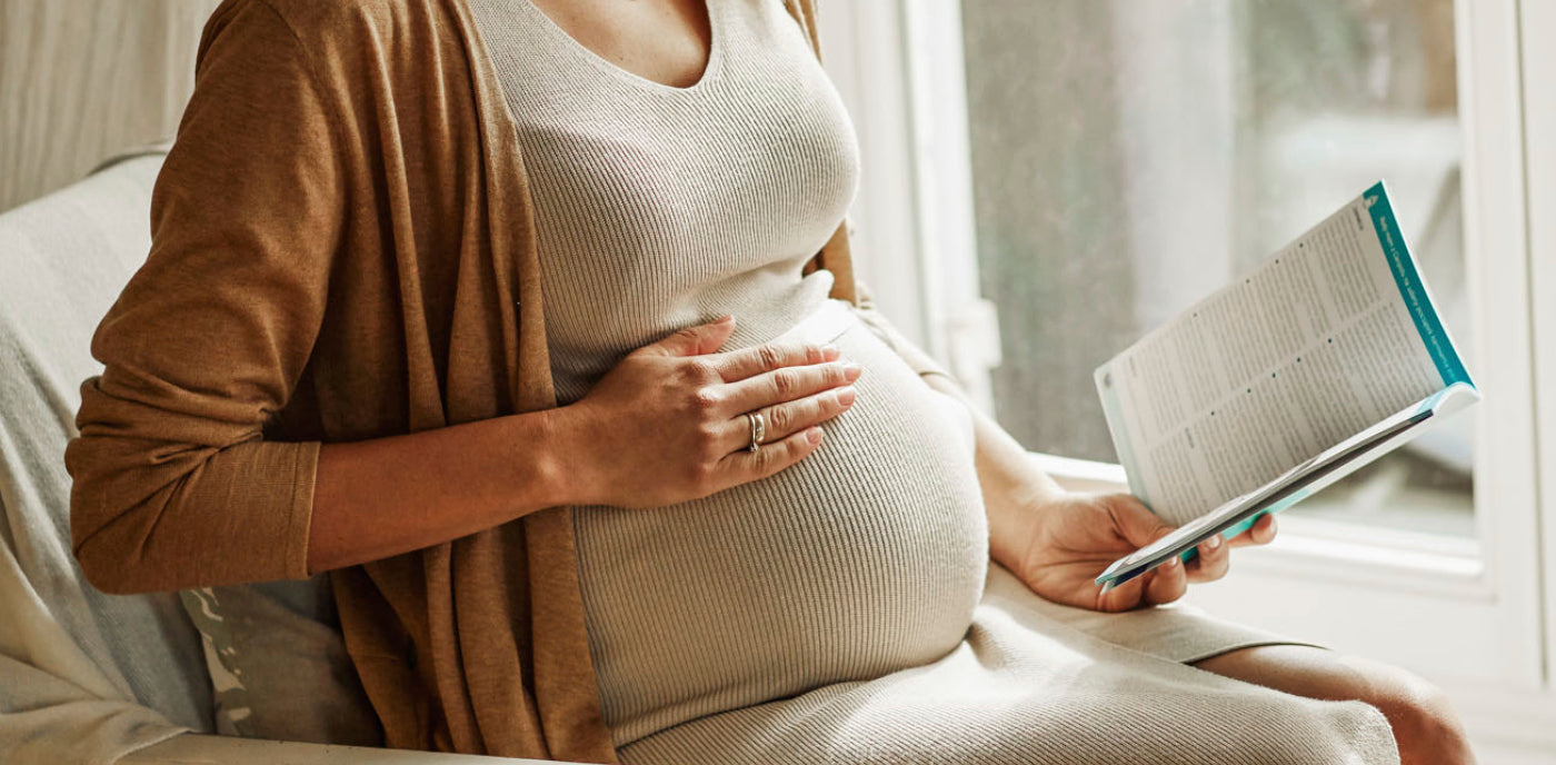 Femme enceinte posant la main sur son ventre, illustrant les expériences et changements possibles lors d’une deuxième grossesse.